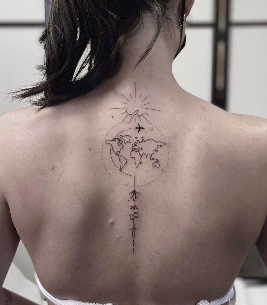 Fineline Tattoo Wien – minimalistisches Reise-Motiv mit Weltkarte